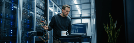 Technicien informatique vérifiant des serveurs dans un centre de données moderne.