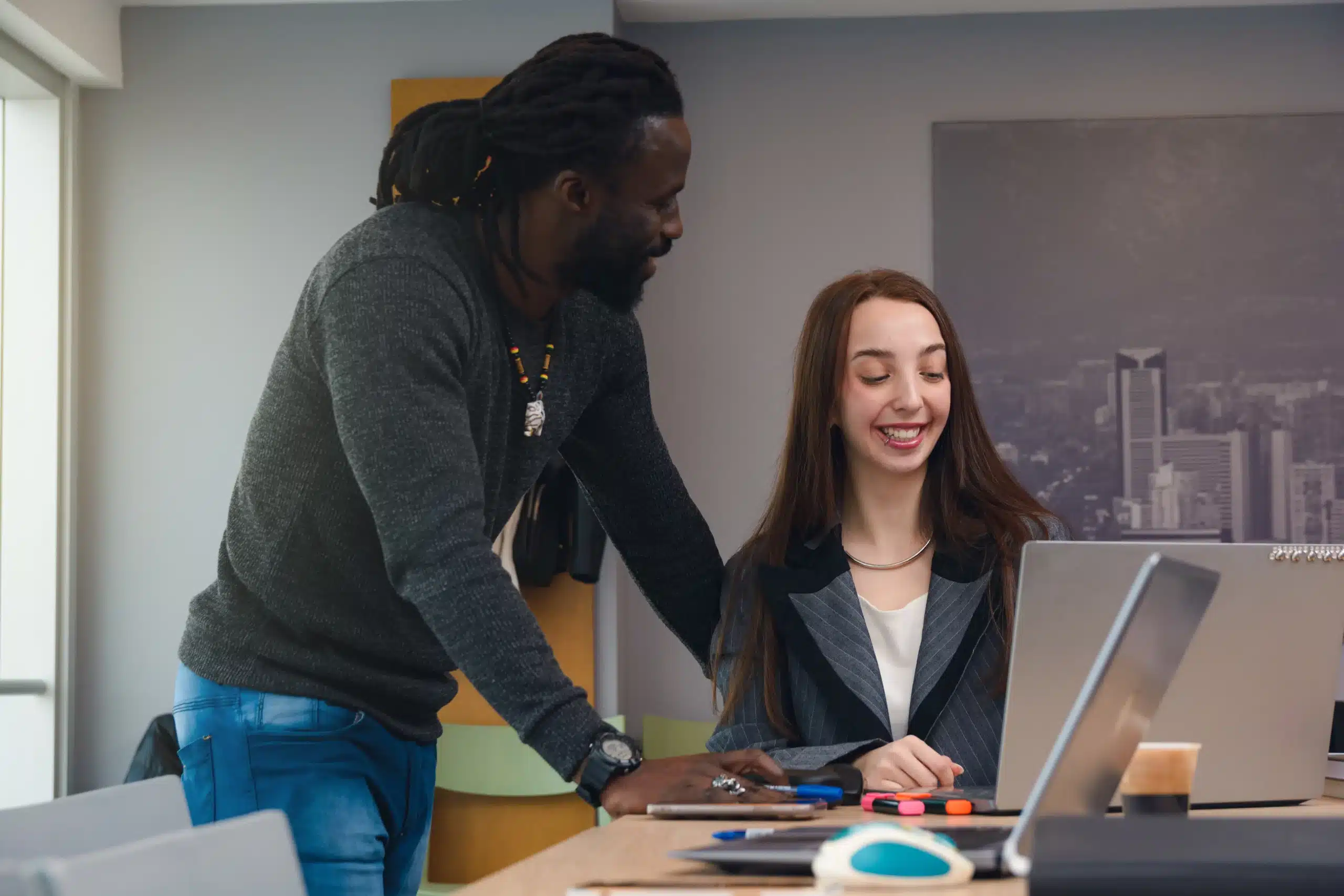Deux apprenants en alternance IA échangeant autour d’un projet sur ordinateur dans un cadre professionnel