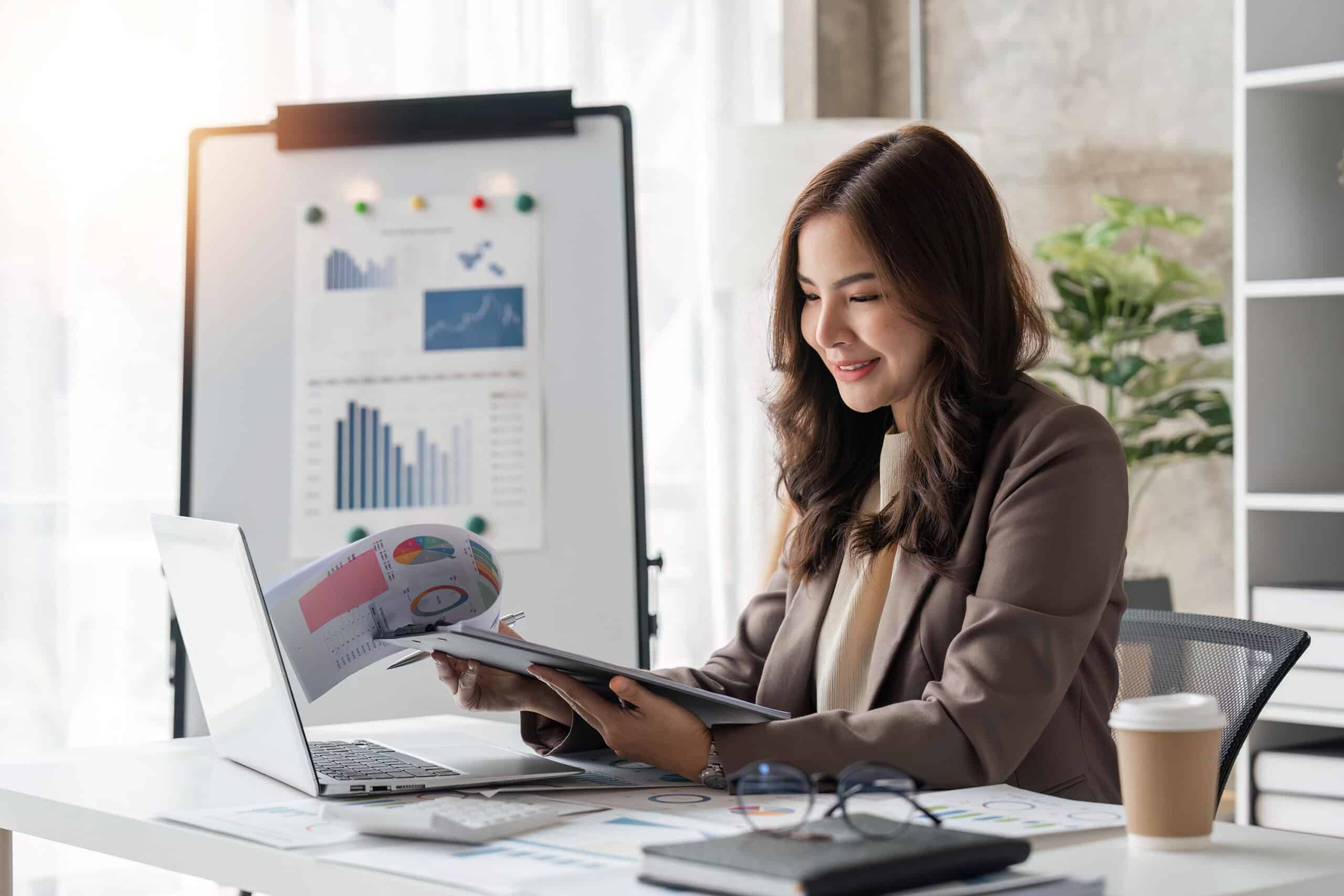 Data analyste utilisant un outil indispensable pour créer des visualisations de données, elle a un document avec des graphiques à la main afin d'identifier des tendances.