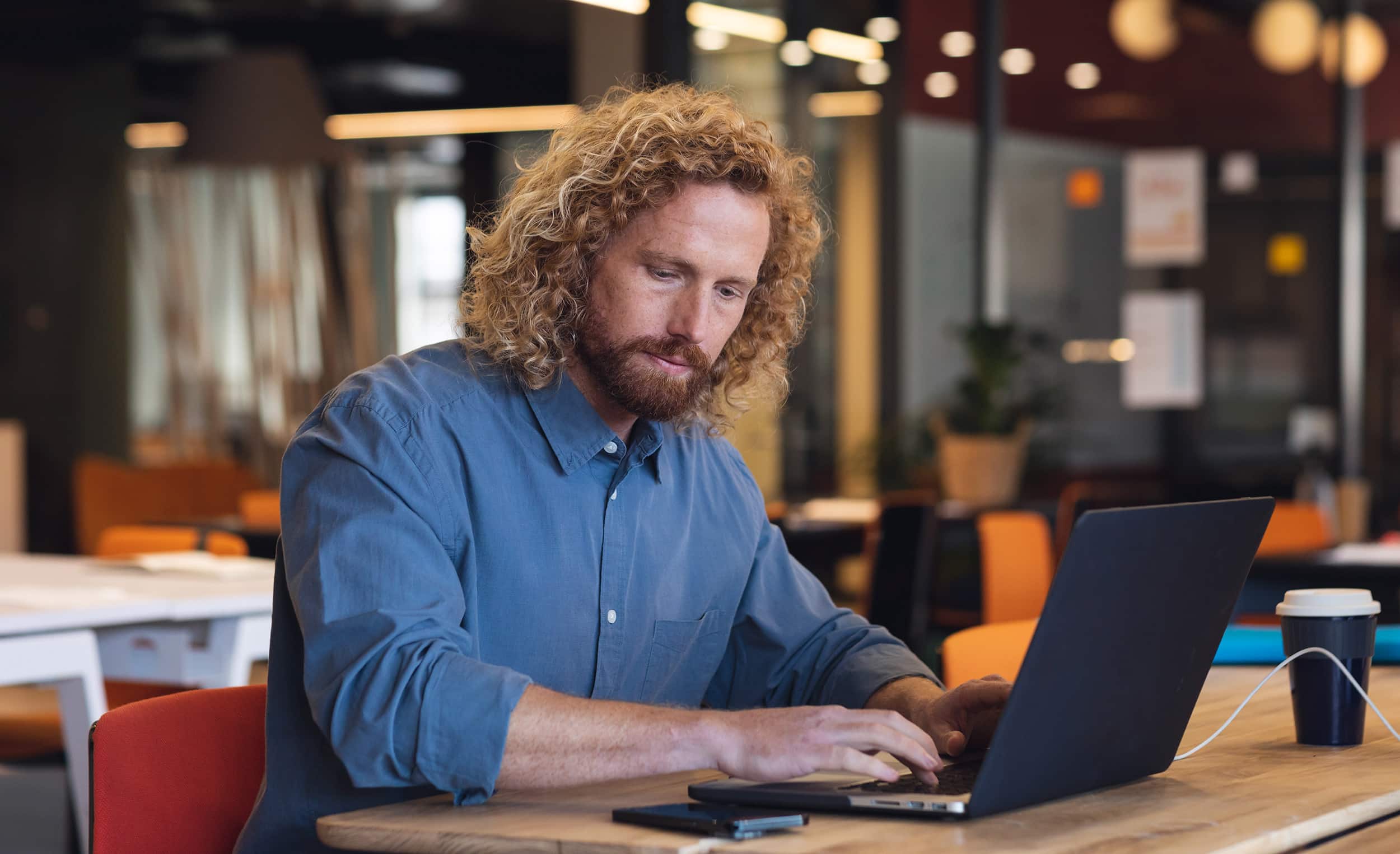 Ingénieur en machine learning travaillant sur son ordinateur portable dans un espace de coworking moderne, illustrant la vie quotidienne d’un expert en intelligence artificielle.