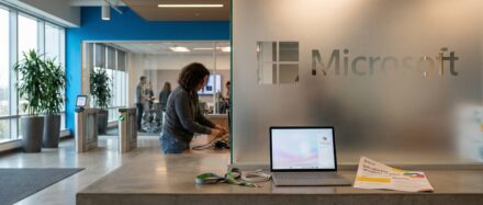 Bureau moderne de Microsoft avec un ordinateur portable et des employés en arrière-plan.