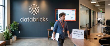 Employé marchant dans les locaux de Databricks avec un panneau de bienvenue pour les visiteurs de Quotient AI.