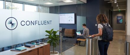 Vue intérieure des bureaux de Confluent avec deux employés qui échangent, mettant en valeur l'environnement de travail moderne.