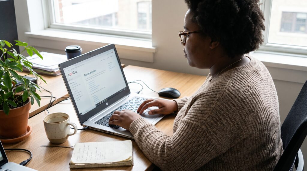 Femme utilisant un ordinateur portable pour développer une application web dans un environnement de bureau lumineux.
