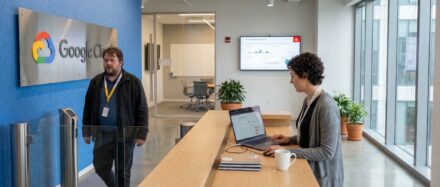 Espacio de oficinas en Google Cloud con un mostrador de recepción y empleados trabajando con portátiles.