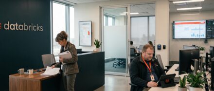 Ein moderner Bürobereich bei Databricks, in dem Mitarbeitende an ihren Schreibtischen arbeiten, mit Fokus auf Teamarbeit und Technologie.