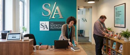 Innenansicht des Büros der Society of Authors mit einem Empfangstresen und Mitgliedern, die sich mit Büchern und Technik beschäftigen.
