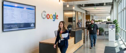 Mitarbeitende in einer modernen Google-Büroumgebung, wobei Cloud Security auf einem Bildschirm angezeigt wird.