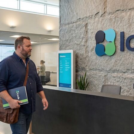 Reception area of Icade featuring a visitor interacting with staff, showcasing modern design and digital displays.